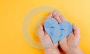 Holding a heart with a smiling face, colorful background with copy space, valintines day photo
