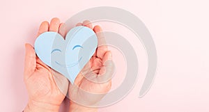 Holding a heart with a smiling face, colorful background with copy space, valintines day photo