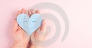 Holding a heart with a smiling face, colorful background with copy space, valintines day photo