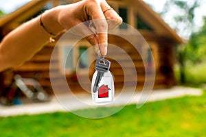 Holding house key with wooden cottage on