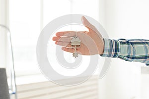 Holding house keys on house shaped keychain in a new home. Mortgage and home loan concept.