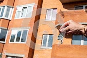 Holding house keys and a house shaped keychain to buy a new house.