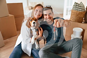 Holding keys for new appartment. Young couple with dog are moving to new home