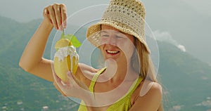 Holding a lemon, girl licks the fruity ice cream outdoors. A woman enjoys a playful moment with a lemon sorbet on a