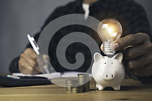 Holding light bulb piggy bank with stack coins and whiting account saving money investment an idea concept