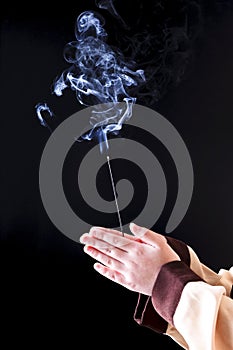 Holding a lit incense stick.