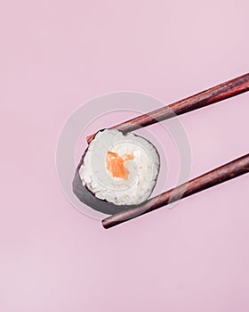 Holding a Maki Sushi Piece with Chopsticks on Pink Background Culinary Gourmet Japanese Food Close Up