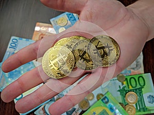 Holding many golden bitcoin coins in hand as a primary source of financial exchange and preferable investment by mining and