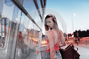 Holding the map, searching the place. Beautiful girl walking near the building and turn around. Photo in motion