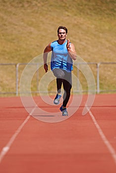 Holding nothing back. Action shot of a young male athlete running on a track.