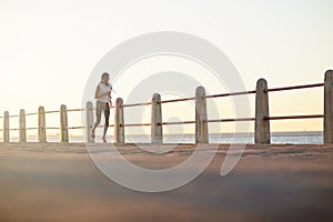 Holding nothing back. A young woman running along the promenade at sunset.