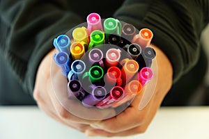 Holding and offering many colorful pens to pick up