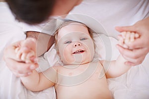 Holding onto her little hands. A devoted young dad holding onto his baby daughters hands.