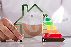 Holding outline of house model with energy efficiency rate