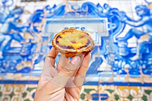 holding Pastel de nata in Porto Portugal in front of beautiful white blue azulejo tiles photo