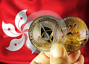 Holding a physical version of Bitcoin (the new virtual currency) and a Hong Kong flag