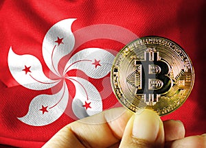 Holding a physical version of Bitcoin (the new virtual currency) and a Hong Kong flag