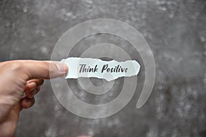 Holding piece of paper with THINK POSITIVE text on it and blur background. Lifestyle concept