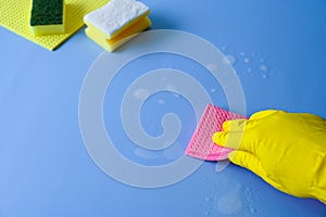 Holding a Pink cleaning sponge on a blue background.