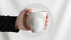Holding a plain white ceramic mug is centered against a neutral