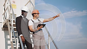 Holding a plan on site at wind turbines field or farm, clean energy source. Eco technology for electric power. industry