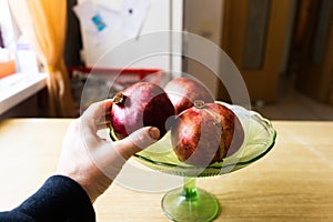 holding a pomegranaten in his hand. basket full of a pomegranates on