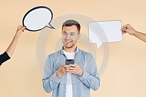 Holding smartphone. Many ideas. Man standing in the studio with empty signs for the text