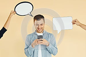 Holding smartphone. Many ideas. Man standing in the studio with empty signs for the text