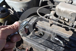 Holding a Spark Plug By Car Engine Under Hood