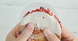 Holding a supreme circular croissant with cream and raspberry topping, close-up video of round shape croissant, hands