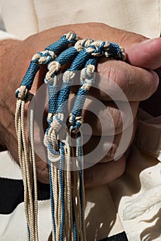 Holding techelet blue tzitzit strings during Jewish prayer