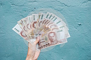 Holding Thai banknote 1000 baht on blue background