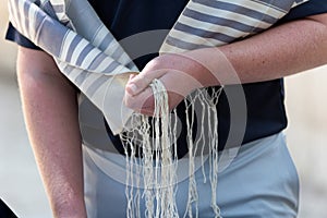 Holding tzitzit strings on a prayer shawl during Jewish prayer photo