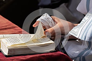 Holding tzitzit and a siddur prayer book during Jewish prayer photo