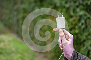 holding an unplugged charger plug - choose the nature over the electronic devices concept