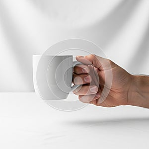 Holding a white ceramic mug with a smooth surface and a simple