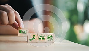 Holding a wooden cube with ESG green icons.