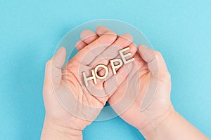 Holding the word hope in the palm of the hands, trust and believe concept, having faith in the future, hopeful positive mindset