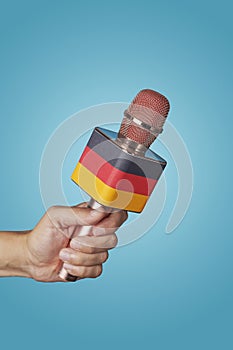 holds a microphone patterned with the german flag