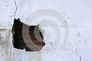 Hole in broken wall and old bricks on a white background. Large crack on the wall of an old brick house, crumbling plaster and