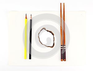 Hole burnt through old paper with pencil and chopsticks