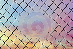 Hole in the center of mesh wire fence on the sky background.