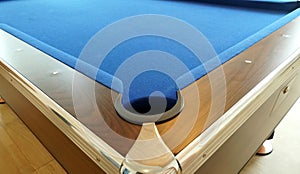 A hole in the corner of a pool table with a wooden border