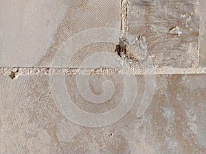 Hole crack in a wall made of stone rock bricks in beige color, damaged wallpaper background on a building