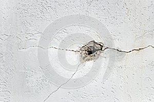 Hole and cracks in concrete white wall with copy space