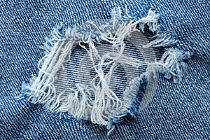 Hole in denim close-up. Ripped blue jeans