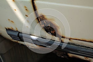 Hole in door and threshold of old car, damaged by rust and corrosion. Close up.