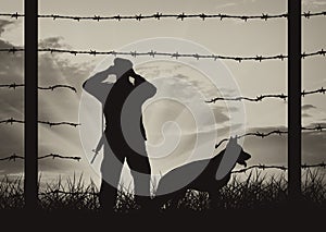 Hole in fence on border and border guards with dog