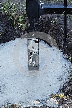 A hole has been filled with concrete to hold the black steel post set in it