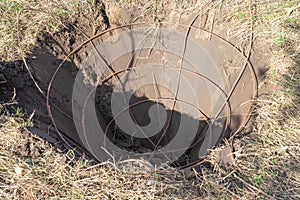 A hole with iron basket in it for tree soil lump forming dug with specialized spade machine for transplanting and transport trees